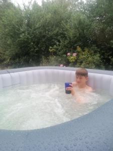 Harbourside House Glengarriff في غليغاريف: صبي في حوض الاستحمام مع هاتف محمول