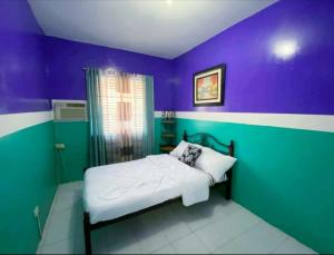 a bedroom with purple and green walls and a bed at Kalai's Rental Dwellings (KRD) in Cotcot