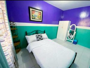 a bedroom with a bed and a purple and green wall at Kalai's Rental Dwellings (KRD) in Cotcot