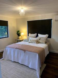 - une chambre avec un grand lit et un lustre dans l'établissement Fig Street Cottage, à Maleny