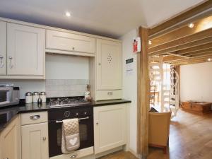 a kitchen with white cabinets and a stove top oven at The Barn in Burley