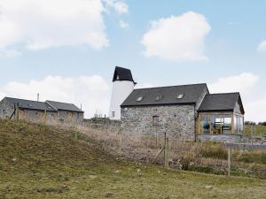 uma casa de pedra com um farol no topo de uma colina em The Top Barn em Coedana