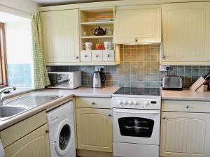 cocina con armarios amarillos y lavavajillas blanco en Strawberie Cottage - E2390, en Stoke Abbott
