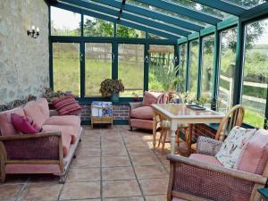 a conservatory with couches and tables and windows at Strawberie Cottage - E2390 in Stoke Abbott