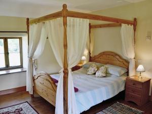 1 dormitorio con cama de madera con dosel y cortinas en Strawberie Cottage - E2390, en Stoke Abbott