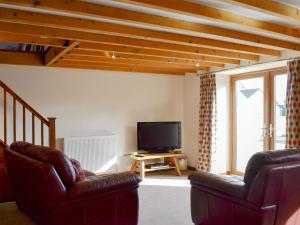 a living room with two chairs and a flat screen tv at Ash Tree Cottage in Gillamoor