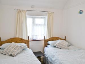 two beds in a small room with a window at Heath View Cottage in Westleton