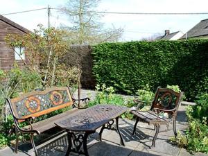 dwie ławki i stół w ogrodzie w obiekcie Heath View Cottage w mieście Westleton