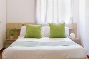 a bedroom with a bed with green pillows and a window at Luchana Apartment in Málaga