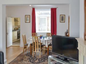 uma sala de jantar com uma mesa e uma televisão em Dolphin Cottage em Newbiggin-by-the-Sea