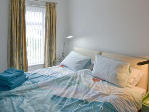 um quarto com uma cama com almofadas e uma janela em Dolphin Cottage em Newbiggin-by-the-Sea