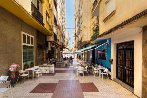 an empty street with chairs and tables and buildings at Luchana Apartment in Málaga