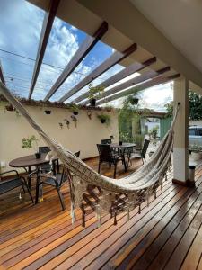 a hammock on a deck with tables and chairs at Pousada Alecrim Dourado in Paraty