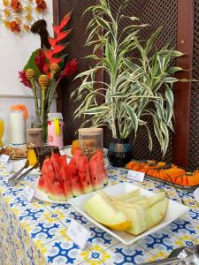 a table with a plate of watermelon and fruit on it at Pousada Alecrim Dourado in Paraty