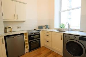 a kitchen with a stove and a dishwasher at Seagulls Nest- stylish 1 bed seafront apartment in Hastings