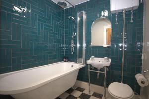a bathroom with a tub and a toilet and a sink at Seagulls Nest- stylish 1 bed seafront apartment in Hastings