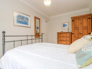 a bedroom with a white bed and a wooden dresser at Oyster Cottage in Falmouth +24 photos