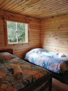 a bedroom with two beds in a log cabin at Cabaña La Troya in Cochamó