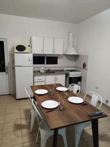 cocina con mesa de madera y electrodomésticos blancos en Jardin del Centro en Villa Elisa
