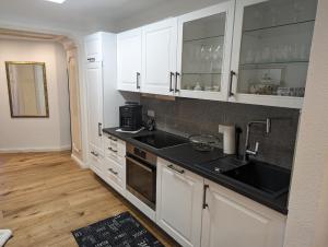 a kitchen with white cabinets and a black sink at foxxbau - urlaubswohnen im Saarschleifenland in Merzig