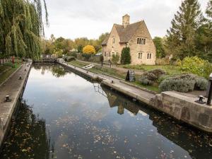 a house sitting next to a river with a building at Midsomer Cottage- Spacious Victorian Cottage with parking & garden - Close to City and ring road in Oxford