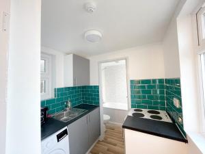 a kitchen with green tile on the walls and a sink at 2 Bed Gem Margate, Free Parking in Kent