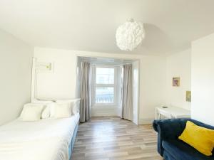 a bedroom with a white bed and a blue couch at 2 Bed Gem Margate, Free Parking in Kent