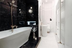een zwart-witte badkamer met een bad en een toilet bij Fabulous and Fancy City Center Designer Apartment in Cluj-Napoca