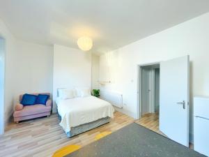 ein weißes Schlafzimmer mit einem Bett und einem Stuhl in der Unterkunft Margate 2 Bed, Prime Location in Kent