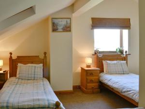 a bedroom with two beds and a window at Hutter Hill Barn West in Silsden
