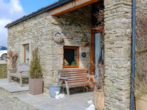 a stone building with a bench in front of it at Hutter Hill Barn West in Silsden