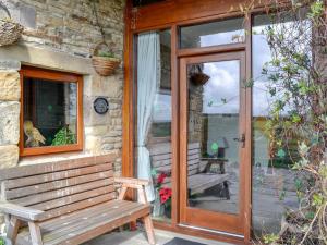 a wooden bench sitting outside of a building with a glass door at Hutter Hill Barn West in Silsden