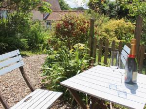 a white picnic table with a bottle of wine on it at Blacksmiths Cottages in Stiffkey