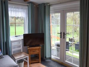 a living room with a flat screen tv next to a window at The Shack in Beck Hole