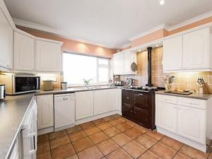 a large kitchen with white cabinets and a large window at Seacot in Runswick