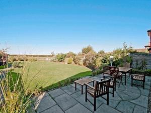 a patio with tables and chairs and a field at Seacot in Runswick