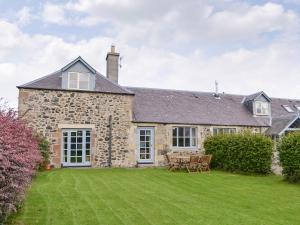 ein Steinhaus mit Rasen davor in der Unterkunft Hume Orchard Steading in Hume