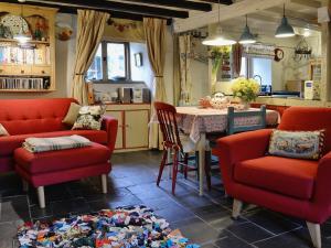 a living room with red chairs and a table and a kitchen at Tremfor - HW7497 in Llwyngwril