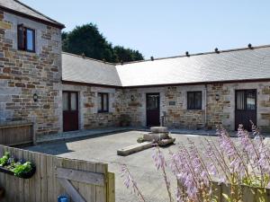 a stone building with a courtyard in front of it at Eglos Derry Farm Cottage - E4597 in Cury