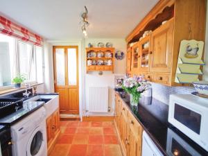 a kitchen with wooden cabinets and a vase of flowers on the counter at Greenbank Cottage in Hilgay