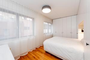 a white bedroom with a bed and a window at Heart of Pärnu Living - Contemporary 2 Bedroom Apartment with Balcony & Parking in Pärnu