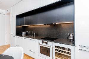 eine Küche mit weißen Schränken und schwarzen Geräten in der Unterkunft Spacious apartment with terrace and grarage in Pärnu