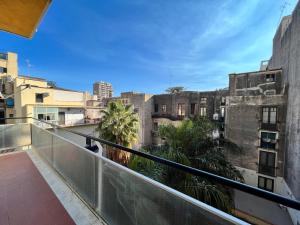 d'un balcon avec vue sur les bâtiments et les palmiers. dans l'établissement Soleluna, à Catane
