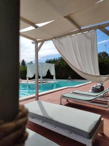 a swimming pool with two beds and an umbrella at Villa con piscina mozzafiato, giardino e barbecue in Polignano a Mare