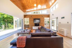 a large living room with a couch and a tv at Inside Out House in Oneroa