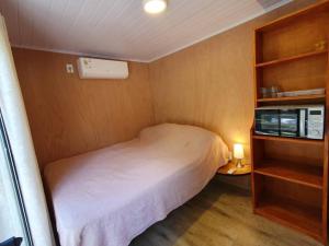 Un pequeño dormitorio con una cama blanca y un estante en Helles, modernes Containerhaus, en Punta del Este