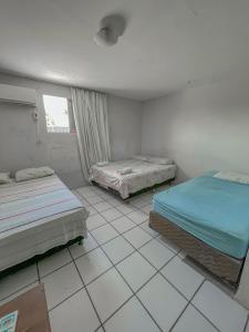 Habitación con 2 camas y suelo de baldosa. en Pousada da Praia, en Recife