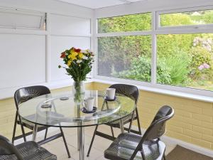 a dining room with a glass table and chairs and windows at Sea View in Hastings