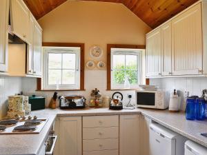 a kitchen with white cabinets and white appliances at Achavalich Cottage- 28330 in Clachan