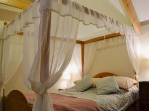 a bedroom with a canopy bed with white curtains at Gareth - 19077 in Carew
